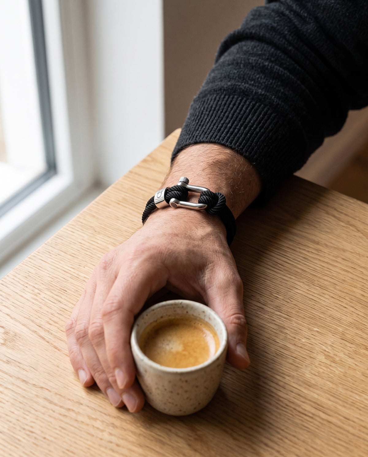 Halyard bracelet on a wrist, hand around an espresso cup