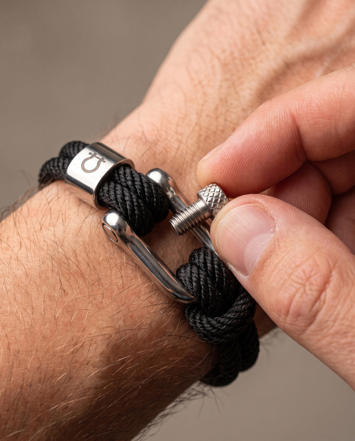 Fingers unscrewing the threaded pin of the Halyard shackle